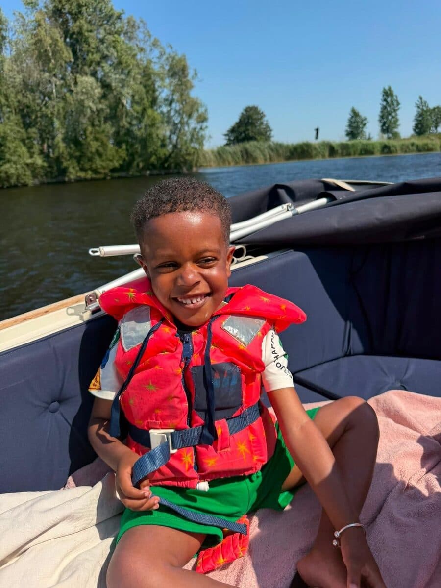 Een stralend kind in een rood zwemvest op een boot