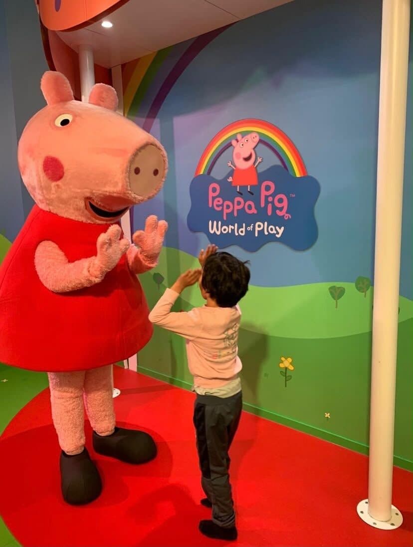 Een kind geeft Peppa Pig een high five