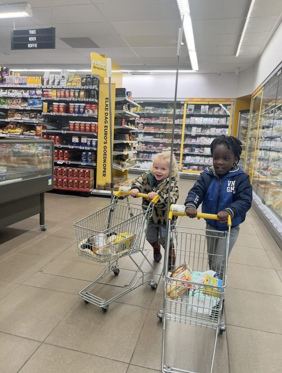 Twee kinderen duwen kleine winkelwagentjes door de supermarkt