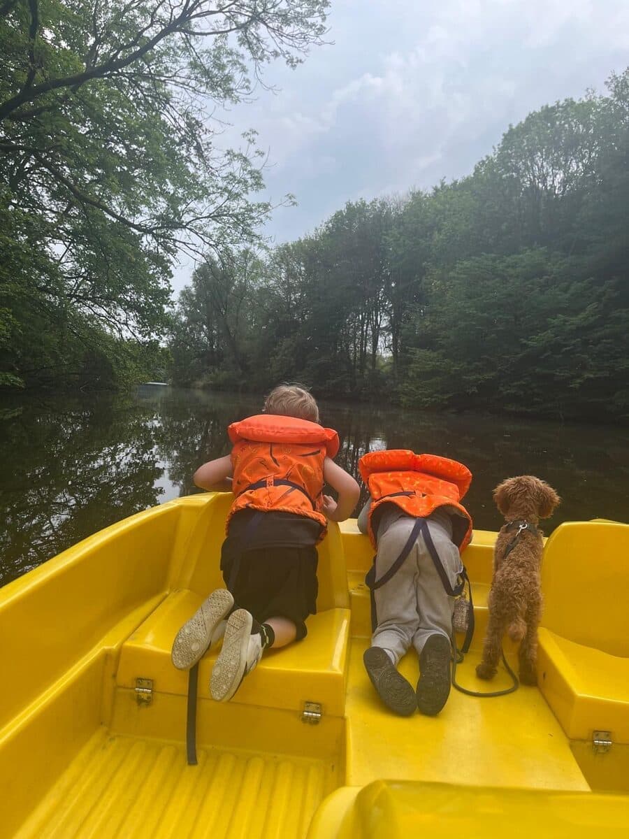 Twee kinderen in zwemvesten en Teddy voorin een gele waterfiets